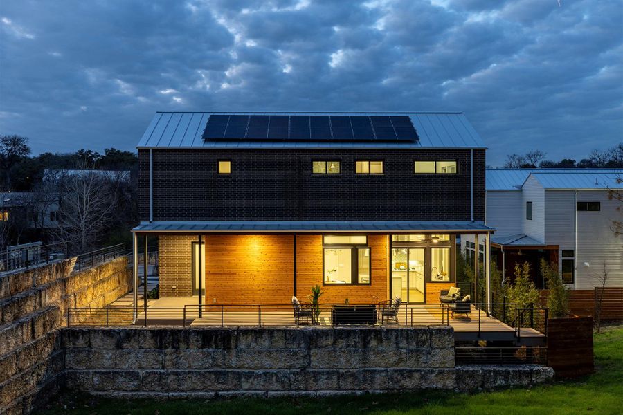 Rear view of house featuring a standing seam roof, a patio area, metal roof, and solar panels