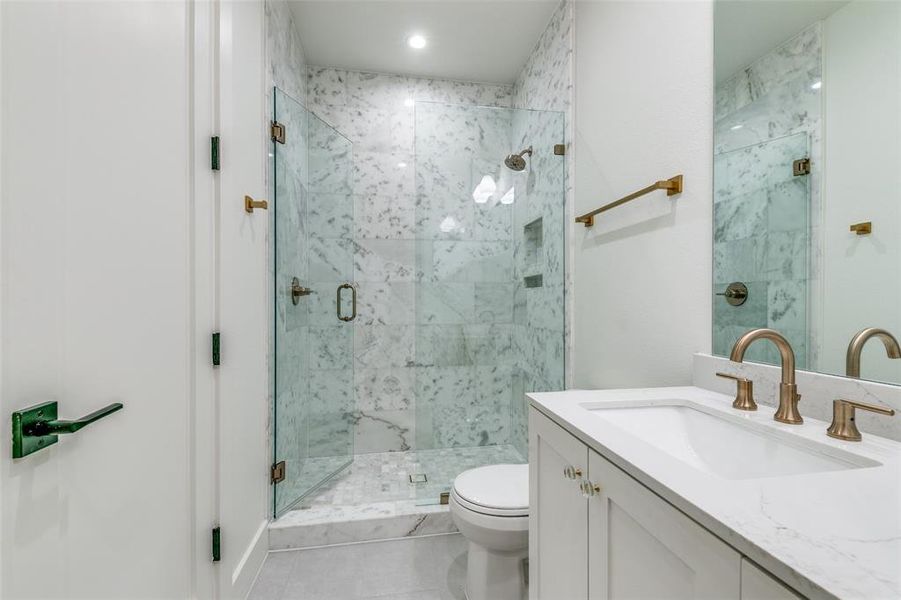 Bathroom featuring tile patterned floors, vanity, walk in shower, and toilet