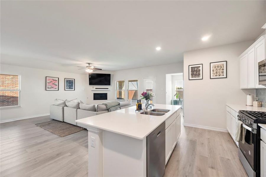 Kitchen with appliances with stainless steel finishes, white cabinetry, a ceiling fan, open floor plan, and light wood finished floors