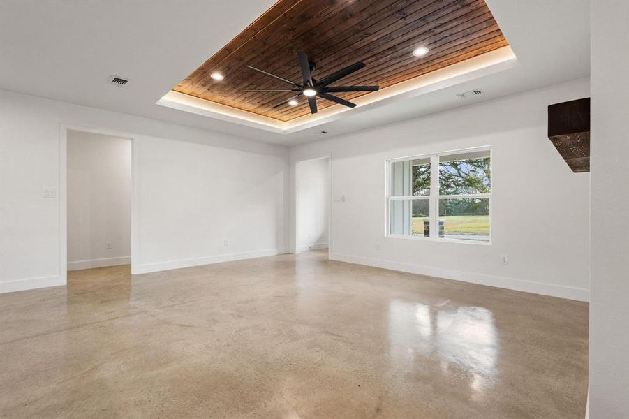 Unfurnished room featuring wooden ceiling, ceiling fan, recessed lighting, concrete floors, and a tray ceiling