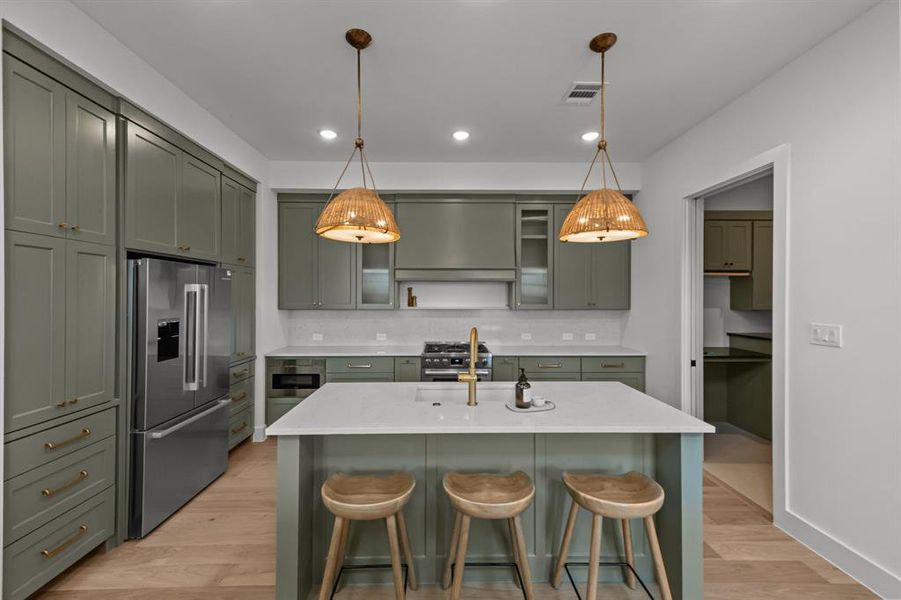 Kitchen featuring appliances with stainless steel finishes, decorative light fixtures, and a breakfast bar