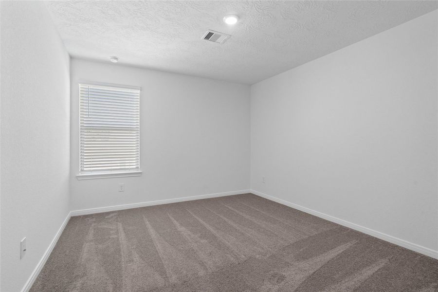 This secondary bedroom offers comfort and style with plush carpeting, neutral paint tones, recessed lighting, large window with blinds, and closet.