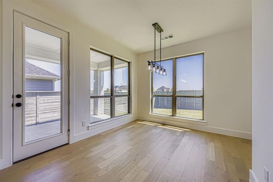 Unfurnished dining area featuring light wood-style flooring and a chandelier Unfurnished dining area featuring light wood-style flooring and a chandelier