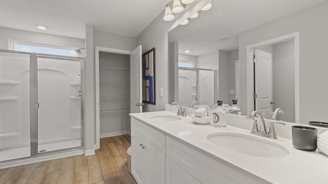 Bathroom with double vanities, quartz countertops, modern fixtures, and large mirror in new townhome at Auburn Ridge.