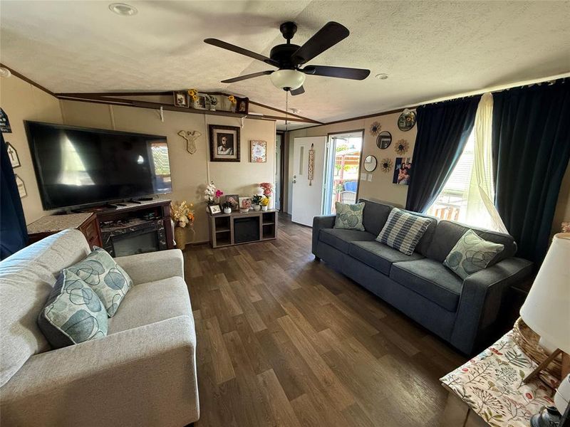 Living area with plenty of natural light, a ceiling fan, and dark wood finished floors