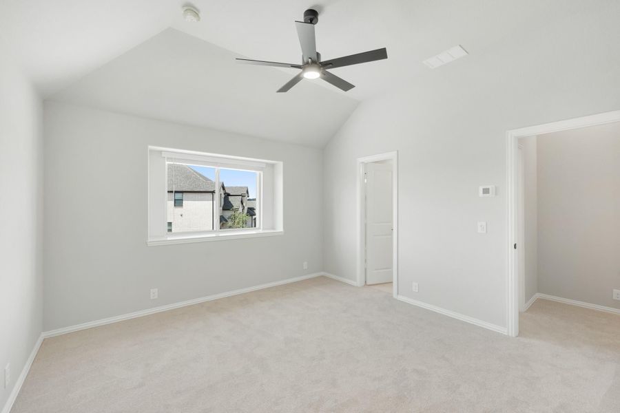 Empty bedroom with vaulted ceiling, ceiling fan, carpet flooring, and a window with neighborhood view Empty bedroom with vaulted ceiling, ceiling fan, carpet flooring, and a window with neighborhood view