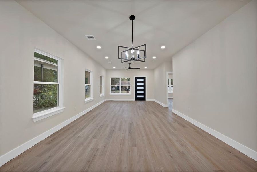 Unfurnished living room with a chandelier, recessed lighting, and light wood-style floors