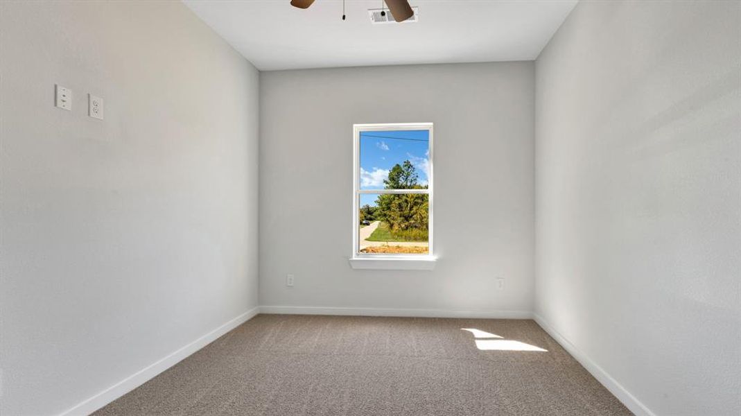 Carpeted spare room featuring ceiling fan