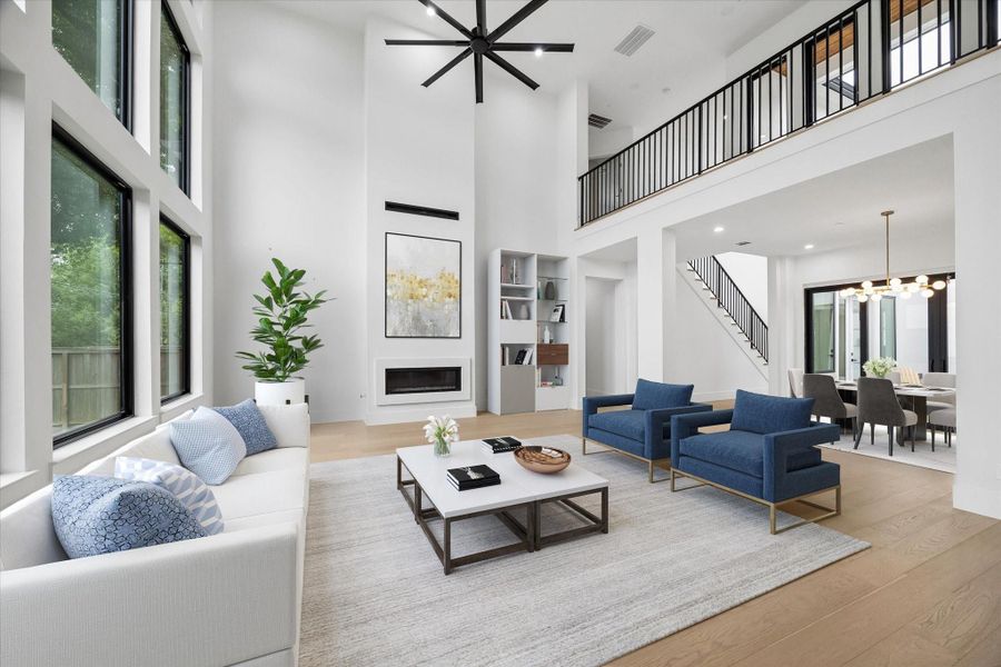 The focus of this great volume of airy space is the Modern Mezza 48 inch linear direct vent gas fireplace, a significant upgrade among many in the home. Iron spindles grace the wide upper bridge overlook and stair railing (virt. staged)