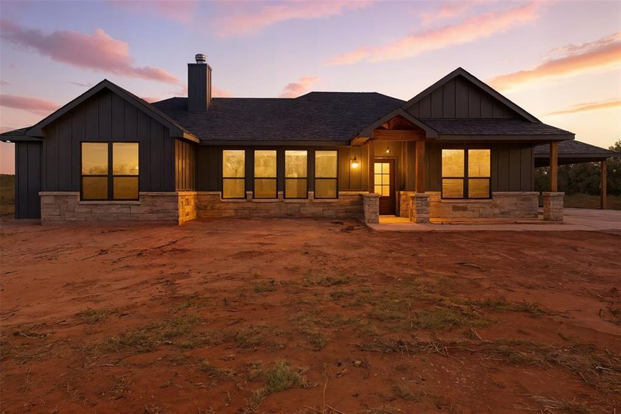 Back of house with board and batten siding, stone siding, roof with shingles, and a chimney Back of house with board and batten siding, stone siding, roof with shingles, and a chimney