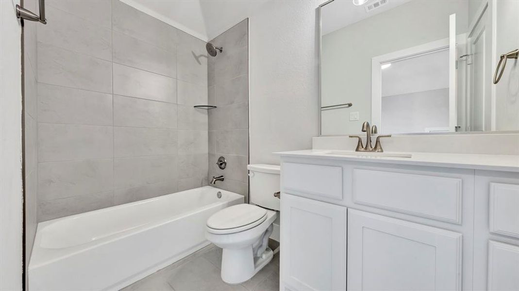 Full bathroom featuring toilet, vanity, and tiled shower / bath