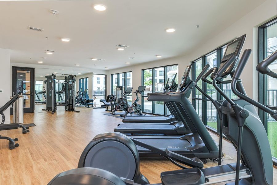 Fitness center featuring wood flooring and a wall of windows providing natural light