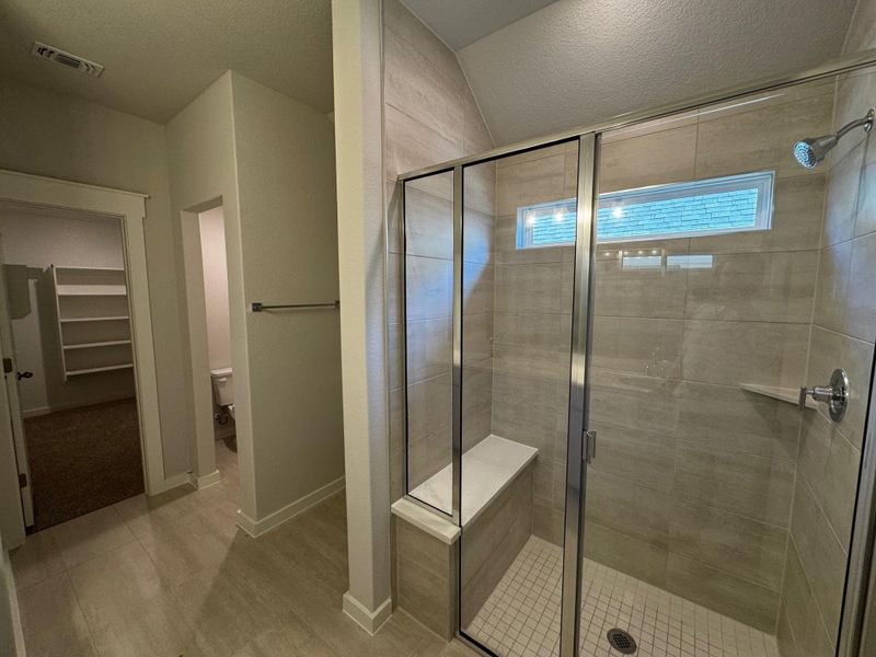 Full bathroom with a stall shower, a spacious closet, a textured ceiling, and light wood-style floors