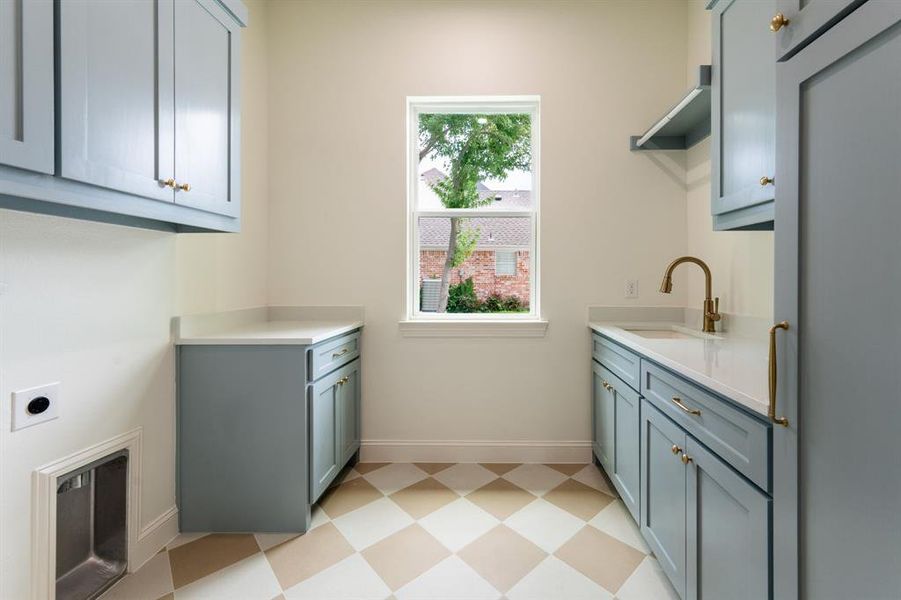 Utility room featuring light blue cabinetry, white countertops, and a checkerboard floor pattern Utility room featuring light blue cabinetry, white countertops, and a checkerboard floor pattern