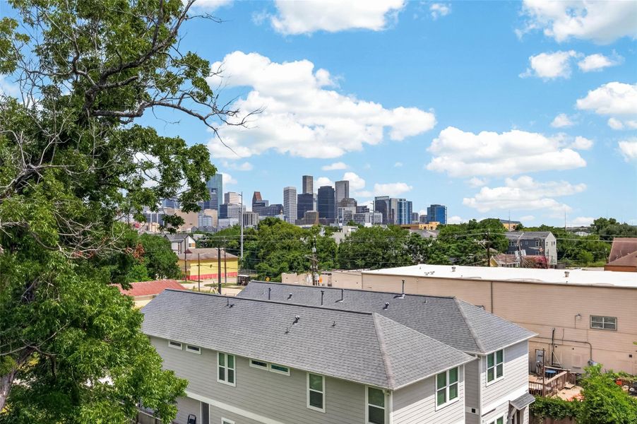 This photo showcases a suburban home with a gray roof and a lush, green backyard. In the background, there's a clear view of a city skyline under a bright blue sky with fluffy clouds, offering a blend of urban and residential appeal. This photo showcases a suburban home with a gray roof and a lush, green backyard. In the background, there's a clear view of a city skyline under a bright blue sky with fluffy clouds, offering a blend of urban and residential appeal.