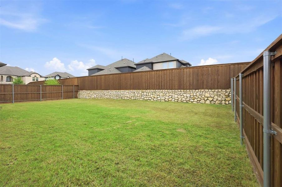 Large backyard with added elevation, offering extra privacy and plenty of space to relax, play, or entertain.