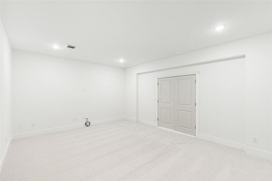 Empty room with white walls, carpet flooring, recessed lighting, and a double closet door