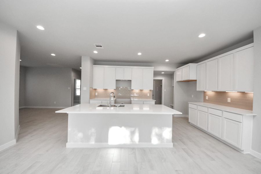 The kitchen is a culinary haven, featuring granite countertops, a tile backsplash, stainless steel appliances, 42” upper cabinets, and undercabinet lighting. Sample photo of completed home with similar floor plan. Actual colors and selections may vary.