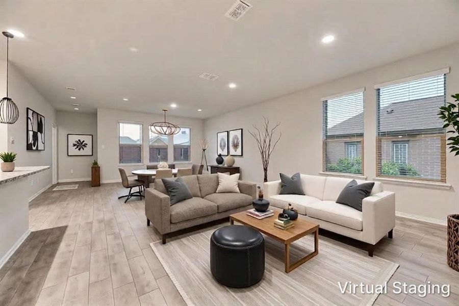Open-concept living space featuring light wood-finish flooring, recessed lighting, and ample natural light from multiple windows