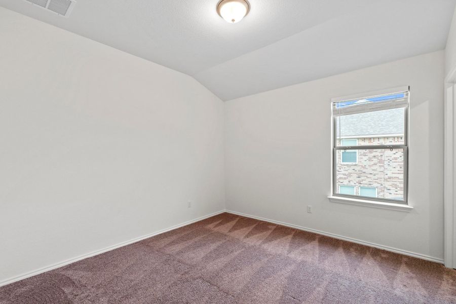 Bedroom featuring a vaulted ceiling, brown carpet, white baseboards, and a double-hung window with blinds