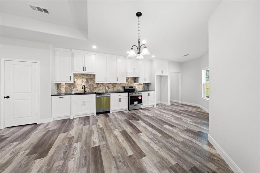 Kitchen with dark countertops, a chandelier, decorative backsplash, stainless steel appliances, and recessed lighting Kitchen with dark countertops, a chandelier, decorative backsplash, stainless steel appliances, and recessed lighting
