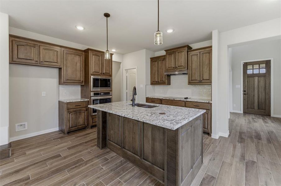 Kitchen island featuring a granite countertop with integrated sink and matte black faucet