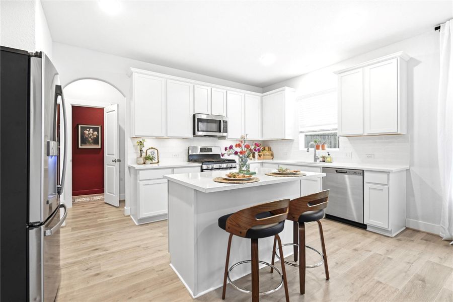 A well-lit kitchen featuring an island with seating, ideal for entertaining and daily meals.