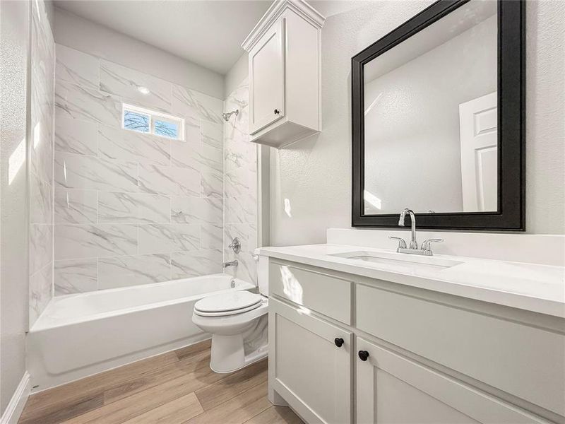 Full bathroom featuring bathtub / shower combination, vanity, and light wood finished floors Full bathroom featuring bathtub / shower combination, vanity, and light wood finished floors