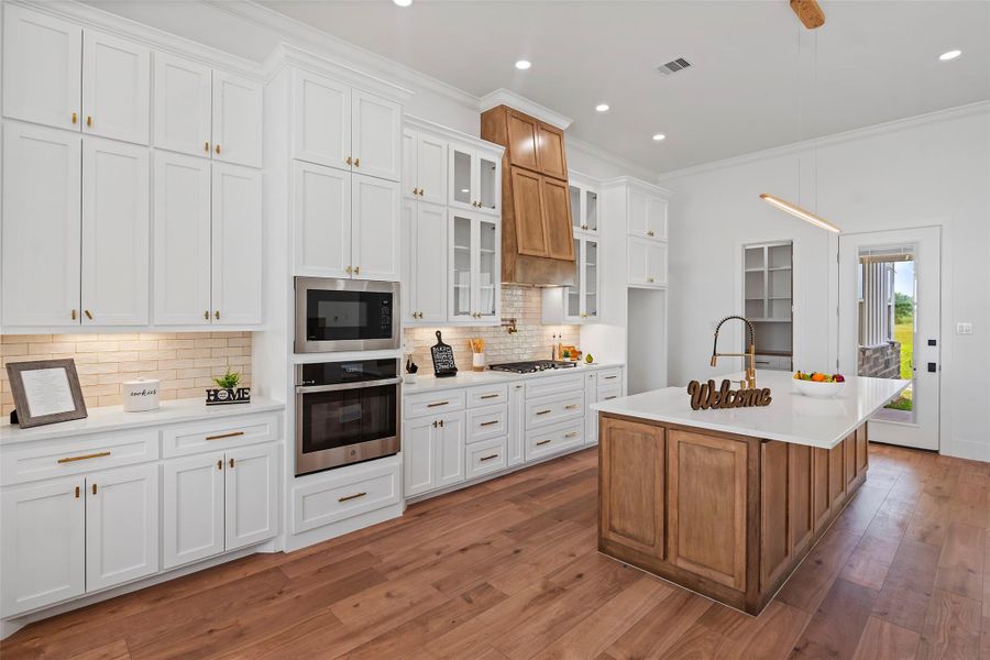 Luxurious kitchen featuring sleek white cabinetry, modern appliances, and a spacious island with elegant wood accents. Perfect for culinary creativity and entertaining.