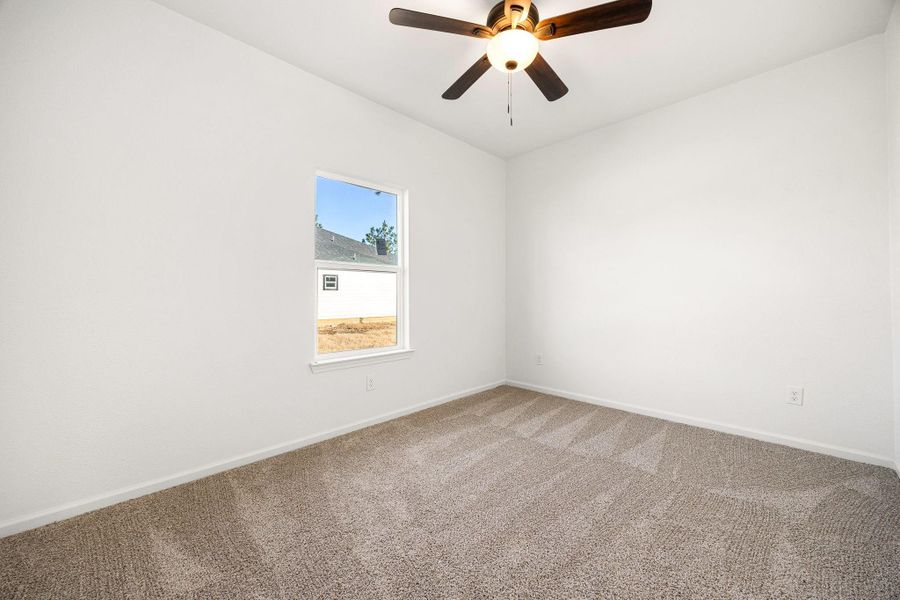 A bright bedroom featuring plush carpeting, a modern ceiling fan, and ample natural light. A bright bedroom featuring plush carpeting, a modern ceiling fan, and ample natural light.