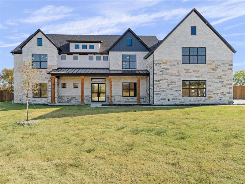 View of front of home featuring covered porch, stone siding, a standing seam roof, and a metal roof