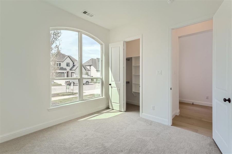 Unfurnished bedroom featuring a spacious closet, a closet, and carpet