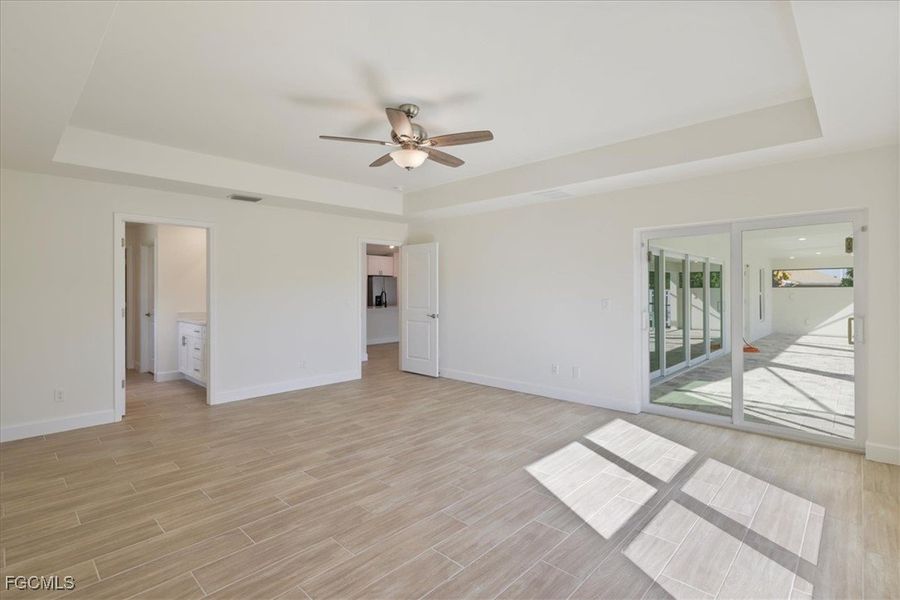 Unfurnished bedroom with a tray ceiling, wood finish floors, and ceiling fan