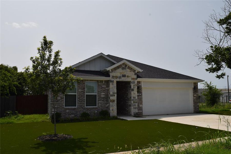 View of front of home with an attached garage, brick siding, driveway, and board and batten siding