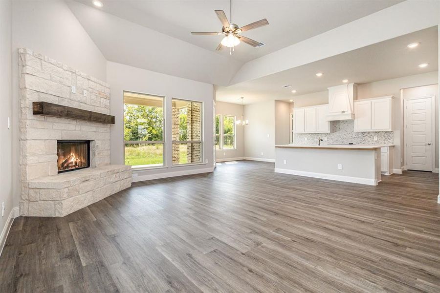 Unfurnished living room featuring recessed lighting, a chandelier, dark wood finished floors, a stone fireplace, and a ceiling fan Unfurnished living room featuring recessed lighting, a chandelier, dark wood finished floors, a stone fireplace, and a ceiling fan