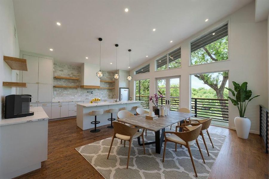 Dining room with dark wood-style flooring, recessed lighting, a towering ceiling, and french doors