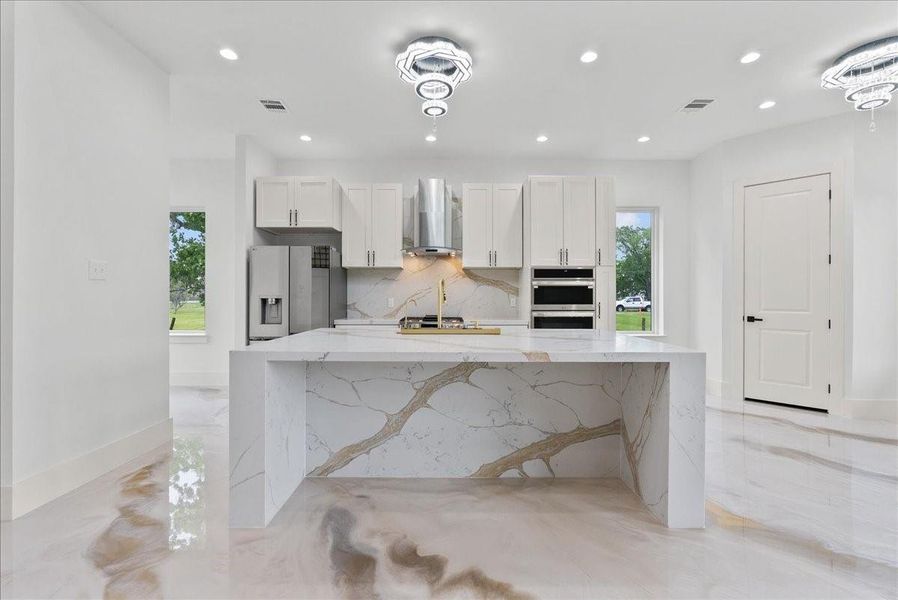 Chef’s kitchen with oversized waterfall island and custom cabinetry.