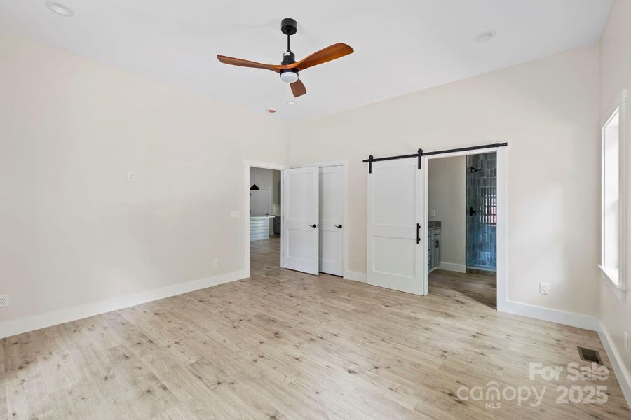 primary bedroom showing barn door for bathroom and closet door primary bedroom showing barn door for bathroom and closet door