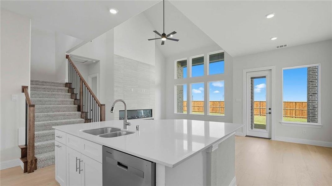 Kitchen featuring light wood-style floors, white cabinets, dishwasher, a kitchen island with sink, and ceiling fan