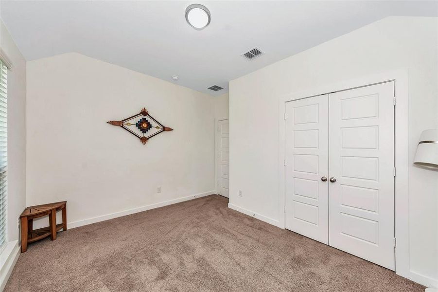 Unfurnished bedroom featuring lofted ceiling, light colored carpet, and a closet