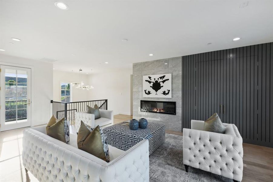 Living room featuring an inviting chandelier, hardwood / wood-style floors, a tiled fireplace, and tile walls