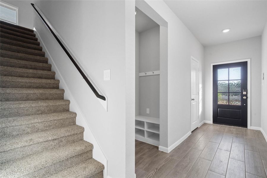 The staircase features plush carpeting for comfort and sound dampening, accented by a modern black handrail that ties into the home's color scheme.