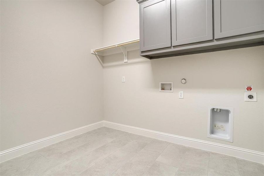 Laundry room with light tile patterned flooring, hookup for an electric dryer, cabinets, and hookup for a gas dryer