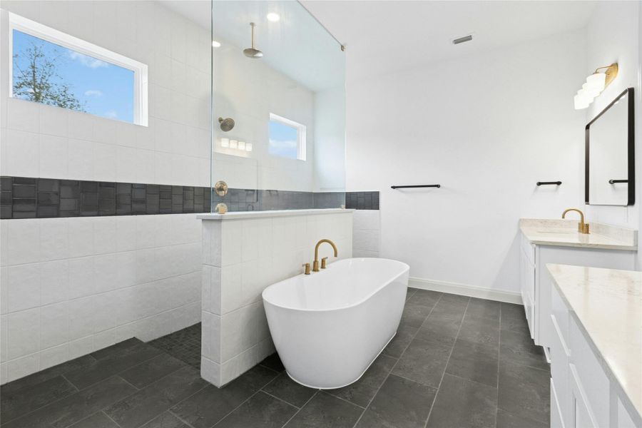Bathroom with a soaking tub, vanity, walk in shower, and dark tile patterned floors Bathroom with a soaking tub, vanity, walk in shower, and dark tile patterned floors