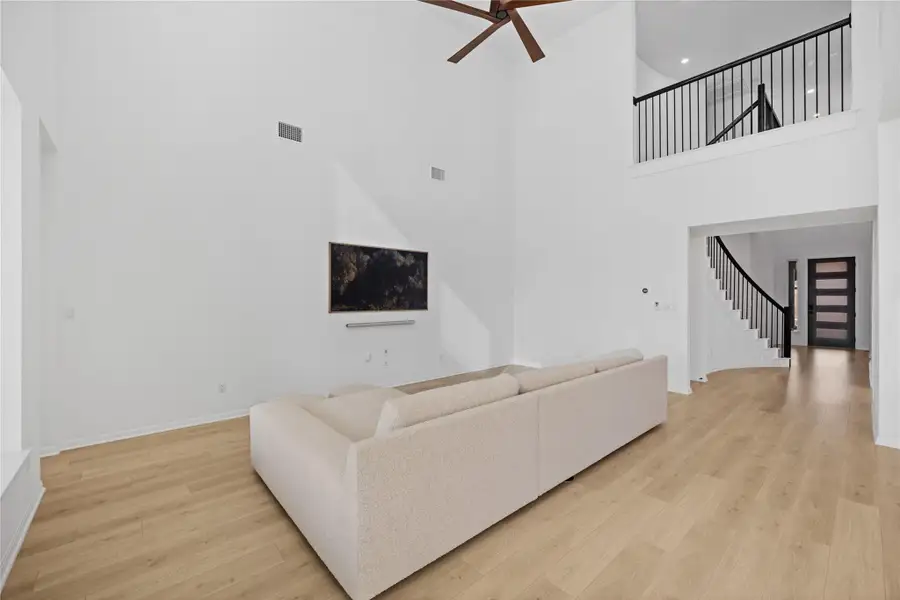 Living area featuring light wood-style floors, a high ceiling, ceiling fan, stairway, and recessed lighting