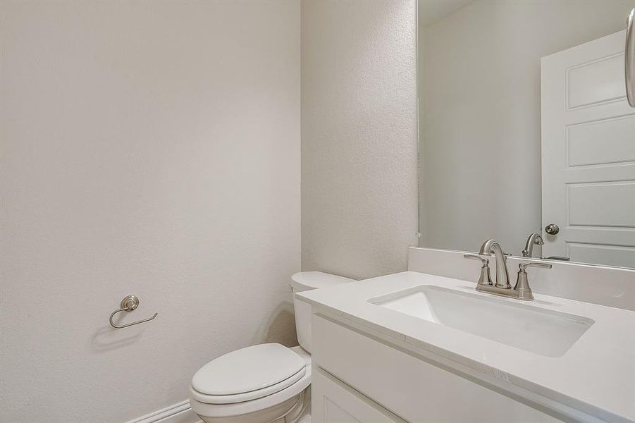 Half bath featuring vanity and a textured wall