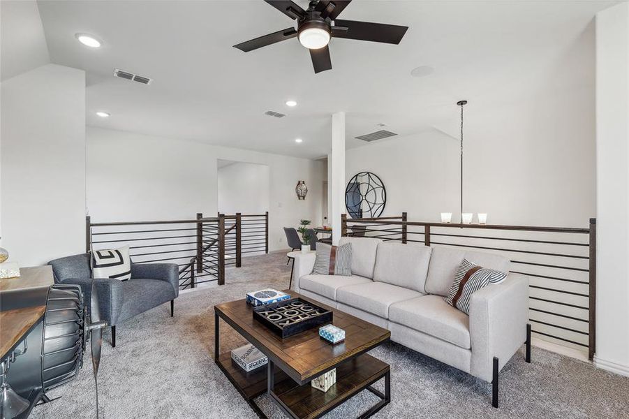 Living room with lofted ceiling, carpet floors, and ceiling fan with notable chandelier