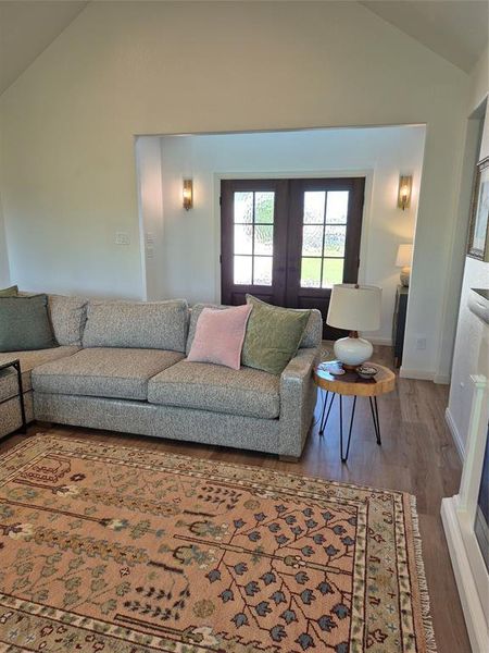 Living room featuring lofted ceiling, french doors, and wood finished floors