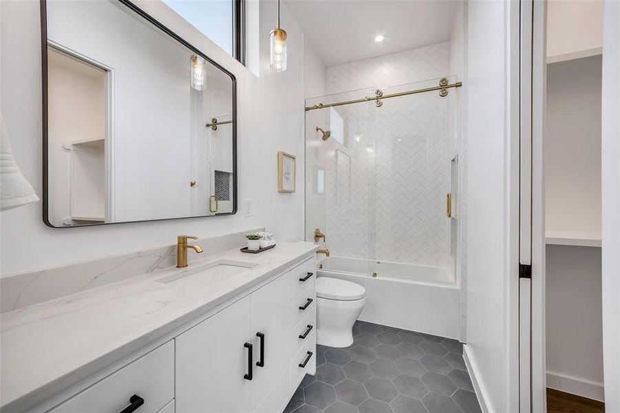 Indulge in sophistication with this guest bathroom's modern design, featuring gold accents and a stylish sliding glass shower door.