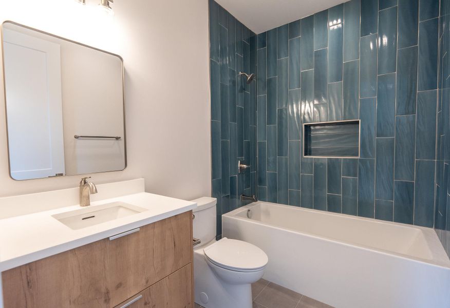 A well-lit bathroom features a modern vanity and a bathtub with rich blue tile surround. A well-lit bathroom features a modern vanity and a bathtub with rich blue tile surround.